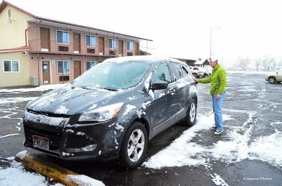 コロラド州の町アラモサのモーテルで車に積もった雪を掃き下ろす