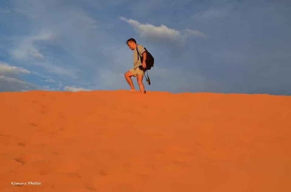 ユタ州のコーラルピンクサンドデューンズ州立公園の砂丘を夕日を受けながら登る男性